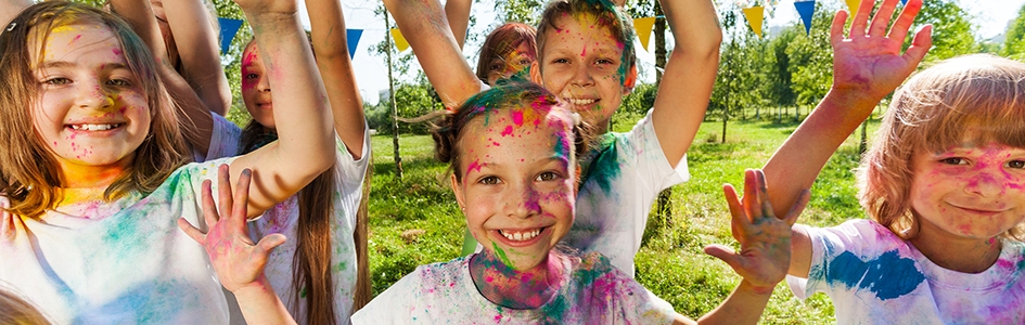Portrait of bright kids smeared in colored powder at the outdoor color festival in summer